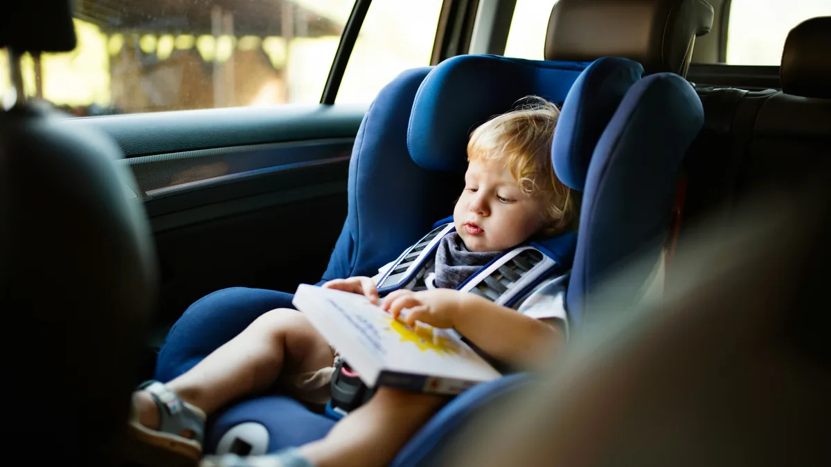 Toddler reading a book in a child car seat – Evenflo Big Kid booster seat class action