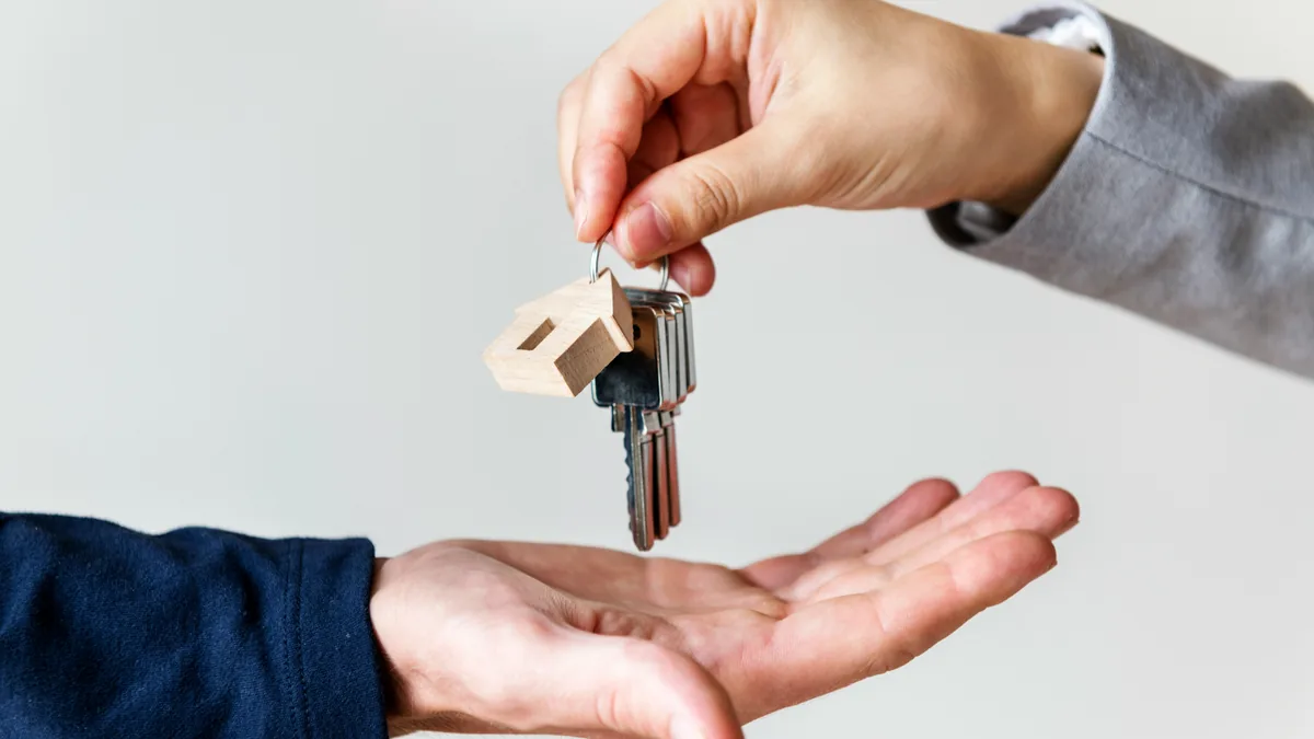 Hand passing house keys to a new owner – Keller Williams and RE/MAX commission class action