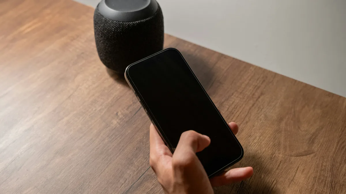 Hand holding a smartphone next to a smart speaker – Apple Siri and Apple Intelligence class action