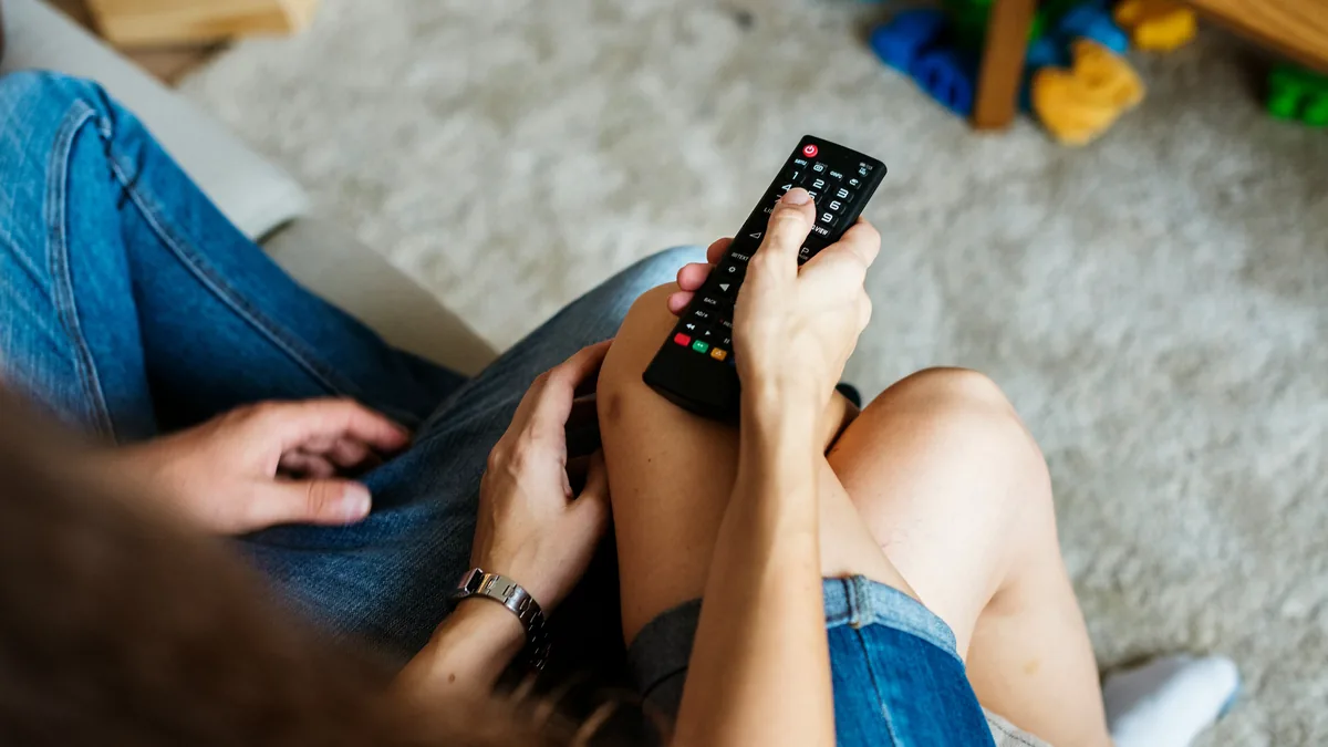 Person holding a TV remote on a sofa – YouTube TV class action
